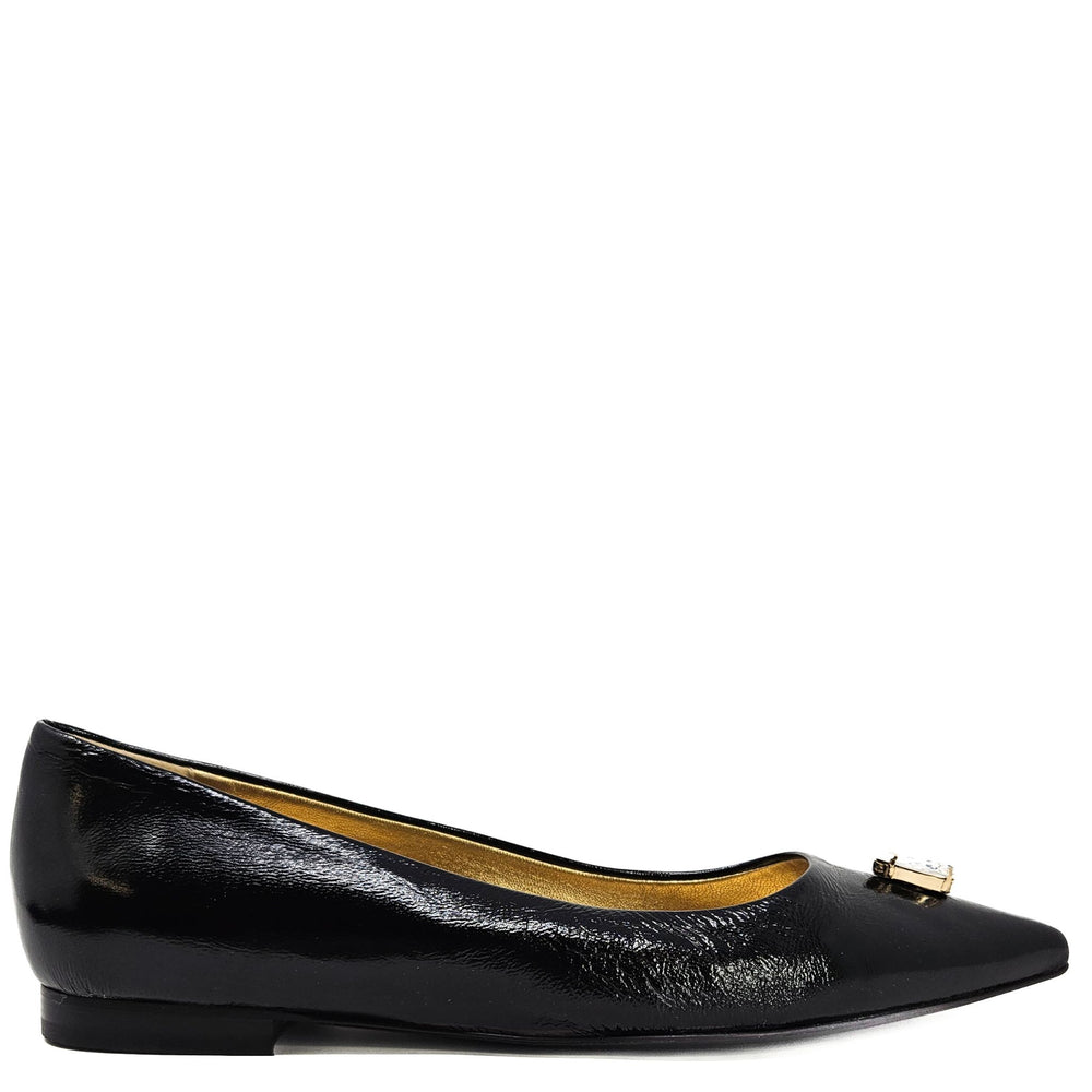 Black patent leather flat shoe with a gold buckle on a white background