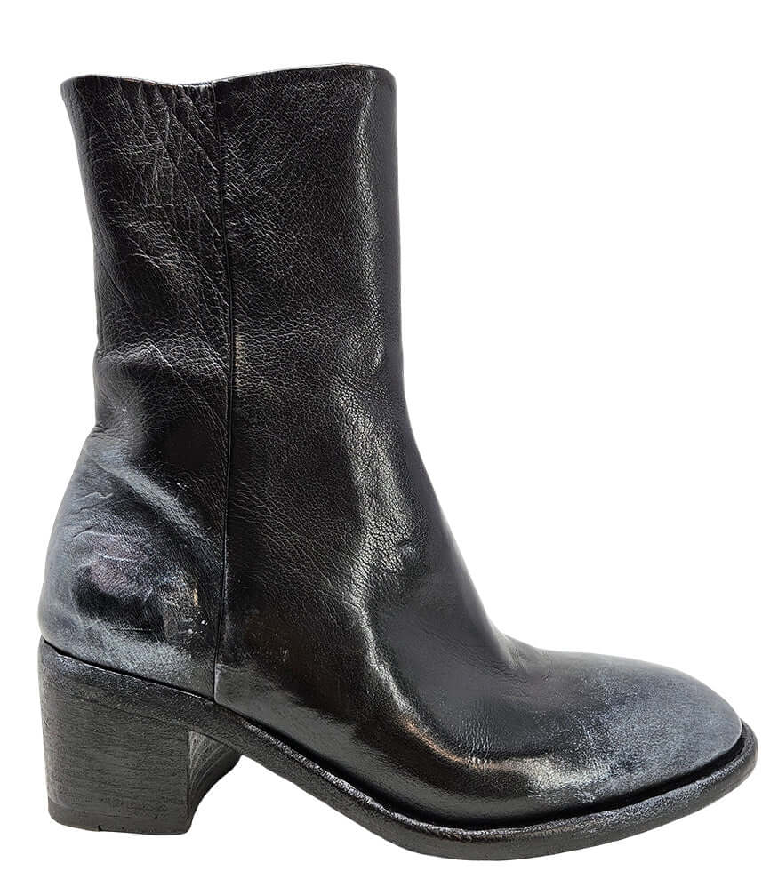 Mid-heel ankle boot crafted from premium leather with a softly rounded toe, artisanal distressed detailing at the toe and heel, and a stacked block heel. Features a full side zipper for easy entry, a leather-lined interior for comfort, and a durable leath