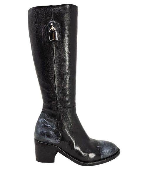 Tall leather boot featuring a softly rounded toe, mid-height stacked block heel, full side zipper for easy on and off, and a decorative metal lock accent near the top shaft. Crafted from premium leather with artisanal distressed detailing at the toe and h