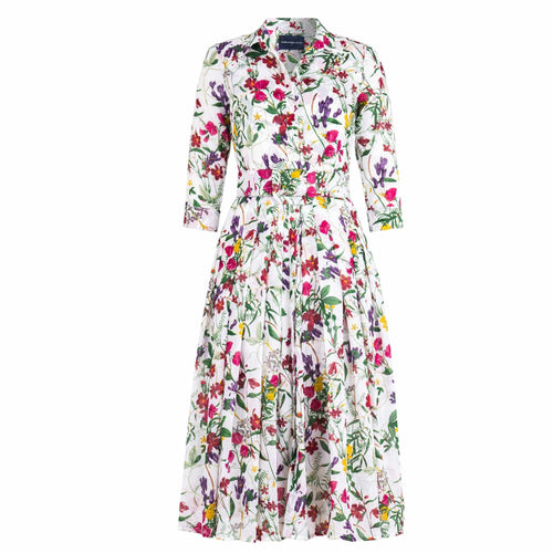 A white midi dress with an all-over print of colorful wildflowers in shades of pink, purple, yellow, and green. The dress has a shirt collar, 3/4 sleeves, a button-front, a pleated A-line skirt, and a matching fabric belt.