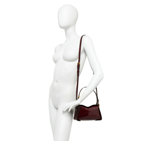 Mannequin holding a brown handbag on a white background
