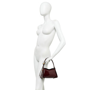 White mannequin holding a brown handbag on a white background