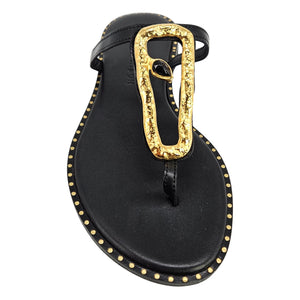 Black sandal with a gold thong on a white background
