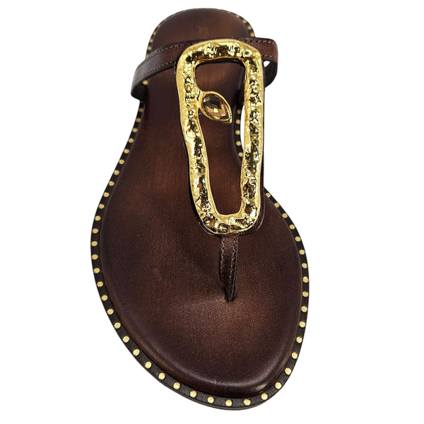Brown sandal with gold embellishments on a white background