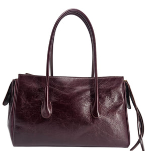 A sleek, burgundy polished leather handbag with two slender top handles and a horizontal gold bar accent on the front.