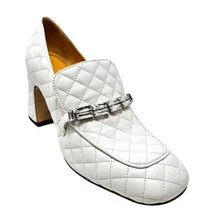 White quilted loafer with a decorative buckle on a white background