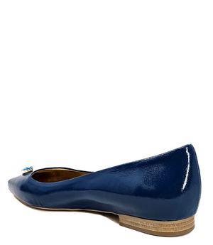 Pointed-toe slingback flat featuring a low block heel, textured fabric upper, slim ankle strap with side buckle, and a large jeweled buckle embellishment on the toe