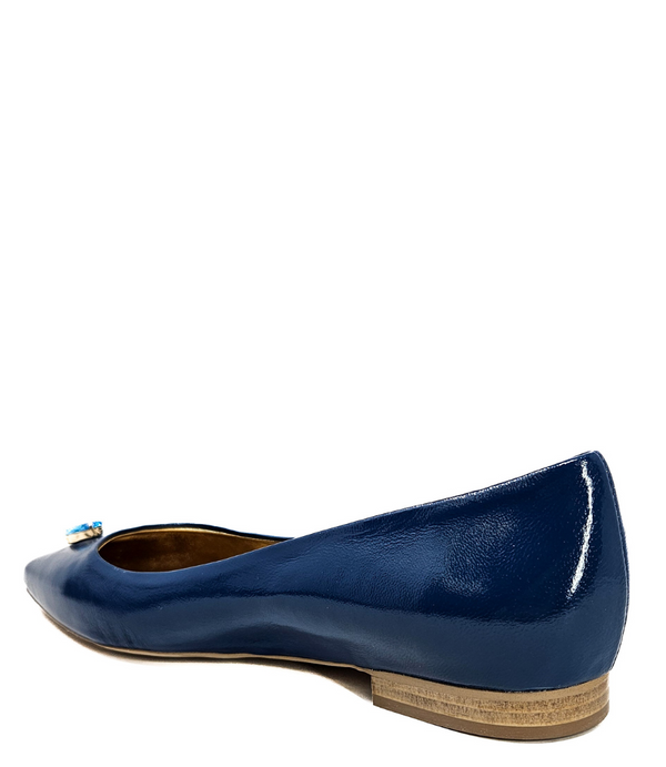 Pointed-toe slingback flat featuring a low block heel, textured fabric upper, slim ankle strap with side buckle, and a large jeweled buckle embellishment on the toe