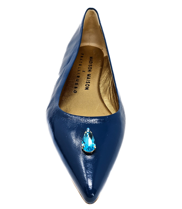 Pointed-toe slingback flat featuring a low block heel, textured fabric upper, slim ankle strap with side buckle, and a large jeweled buckle embellishment on the toe