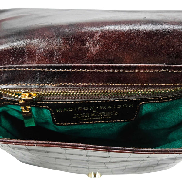 Close-up of a leather handbag with visible wear, featuring a brand label.