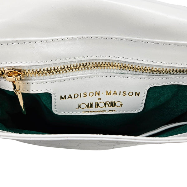 Close-up of a white handbag with gold zipper and visible brand name on a white background