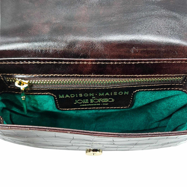 Close-up of a handbag with 'Madison Maison' branding on a white background