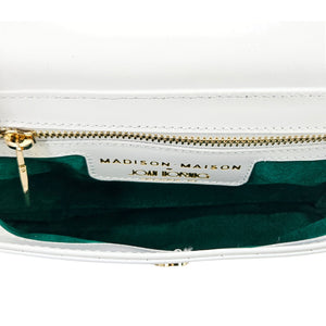 Close-up of a white handbag with gold zipper and 'Madison Maison' branding.