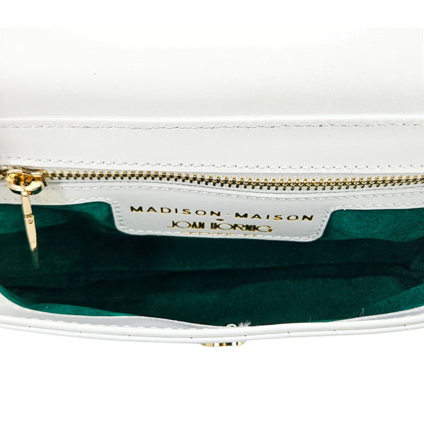 Close-up of a white handbag with gold zipper and 'Madison Maison' branding.