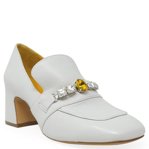 White shoe with a decorative brooch on a white background