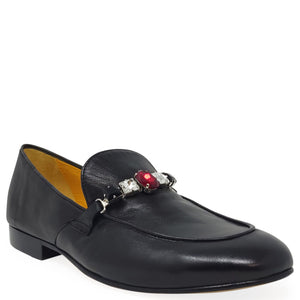 Black loafer with a decorative brooch on a white background