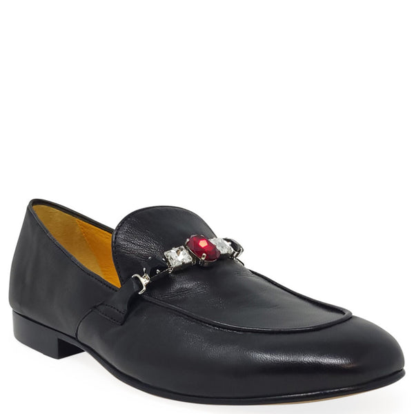 Black loafer with a decorative brooch on a white background