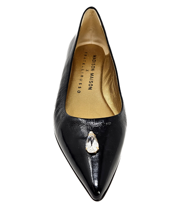 Pointed-toe slingback flat featuring a low block heel, textured fabric upper, slim ankle strap with side buckle, and a large jeweled buckle embellishment on the toe