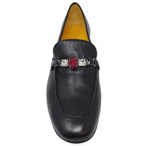 Black loafer with a decorative brooch on a white background