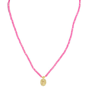Necklace with pink beads and a gold pendant on a white background