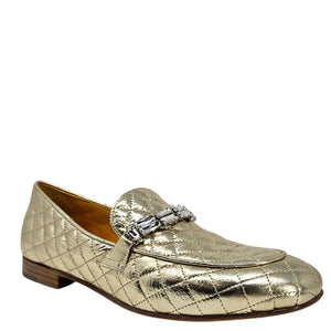 Gold quilted loafer with a decorative buckle on a white background