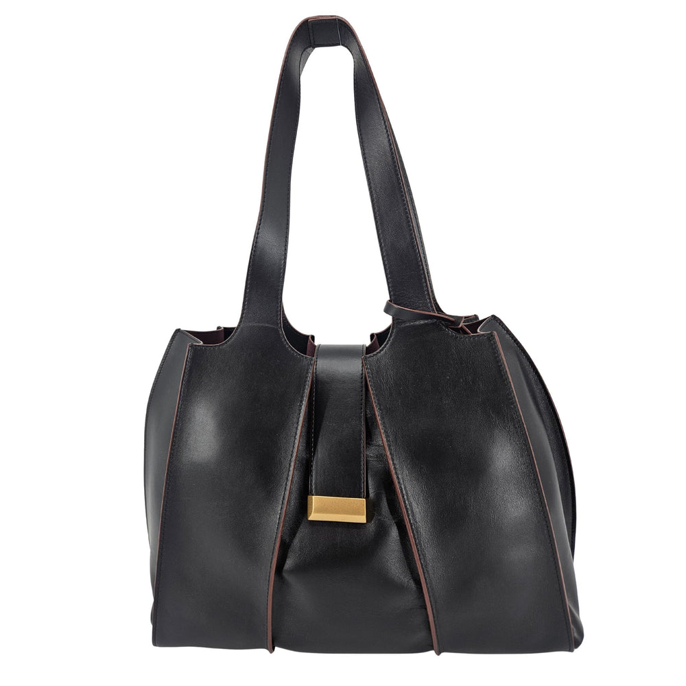 A sleek, black polished leather handbag with a wide opening, two top handles, and a horizontal gold bar accent on the front.