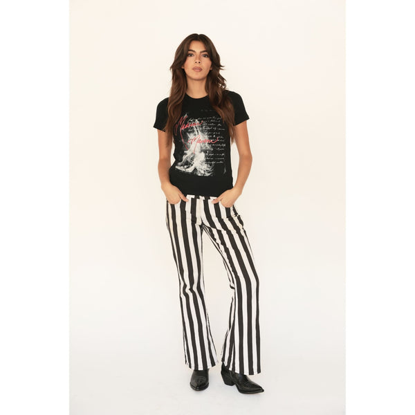 Woman wearing a black graphic t-shirt and black and white striped pants on a white background