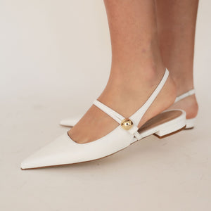 White pointed-toe flats with a gold accent on a neutral background