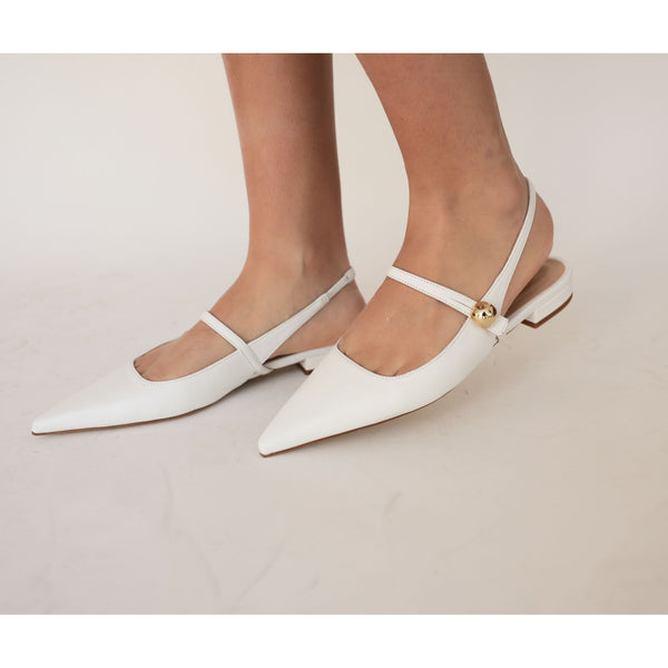 White pointed-toe flats with thin straps on a neutral background