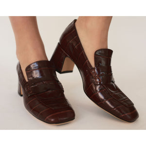Brown crocodile-patterned shoes on a neutral background