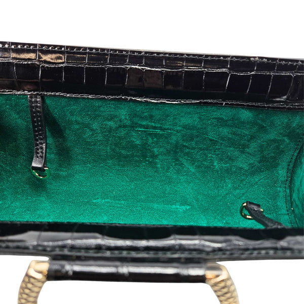 Close-up of a green leather bag with gold accents on a white background