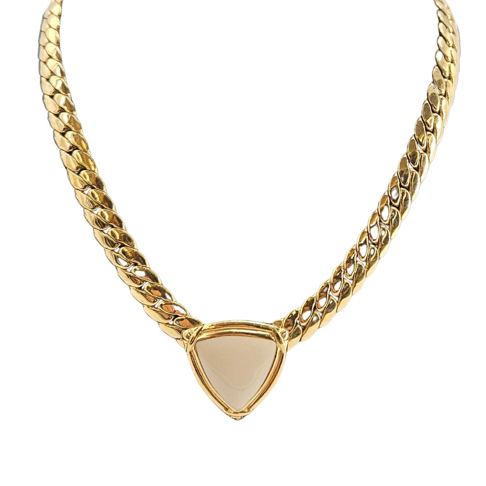 Gold chain necklace with a beige triangular pendant on a white background