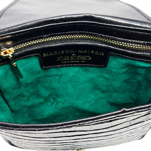 Close-up of a handbag with green interior and visible brand label.