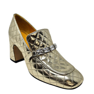 Gold metallic loafers with a decorative buckle on a white background