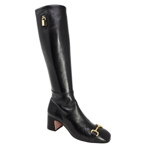 Black knee-high boot with gold hardware on a white background