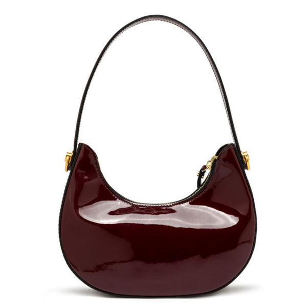 Patent leather handbag with gold accents on a white background