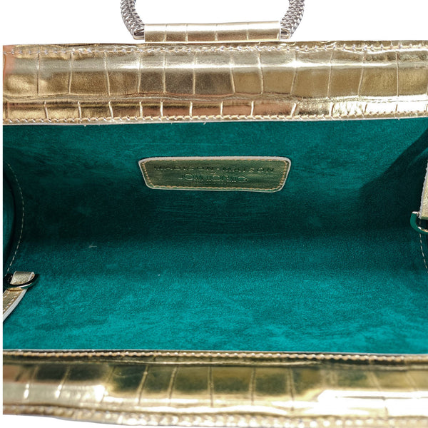 Close-up of a teal handbag with gold accents on a white background