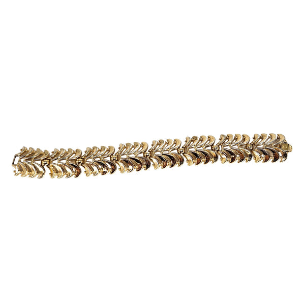 Gold bracelet with leaf-like design on a white background