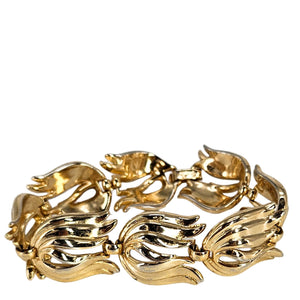 Gold bracelet with leaf-like design on a white background
