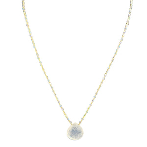 Necklace with a round, textured pendant on a thin chain against a white background