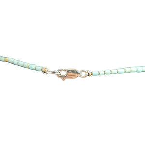 Turquoise beaded bracelet with gold clasp on a white background