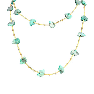 Necklace with turquoise stone beads on a gold chain against a white background