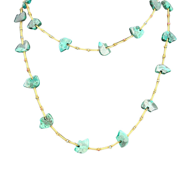 Necklace with turquoise stone beads on a gold chain against a white background