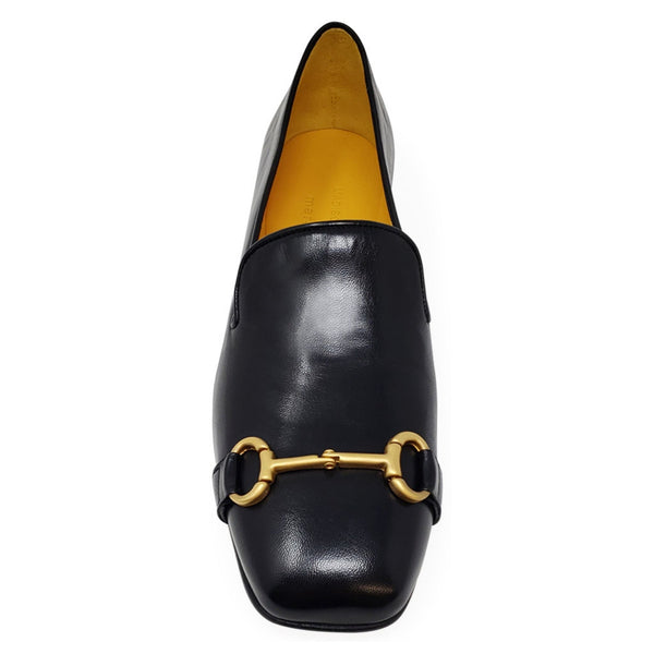 Black loafer with gold horsebit on a white background
