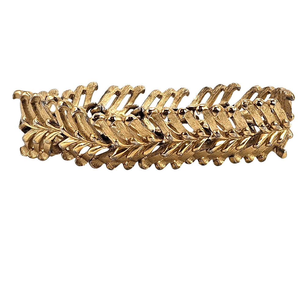 Gold bracelet with leaf-like design on a white background