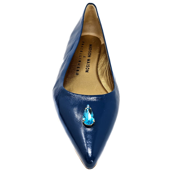 Blue pointed-toe shoe with a blue gemstone on a white background
