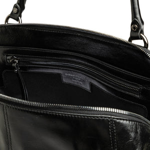 Close-up of a black leather bag with visible brand name, open to show interior.