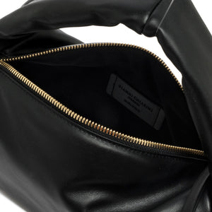 Close-up of a black leather bag with gold zipper, brand label visible.