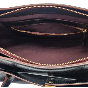 A sleek, black leather handbag with two slender top handles and a horizontal gold bar accent on the front.