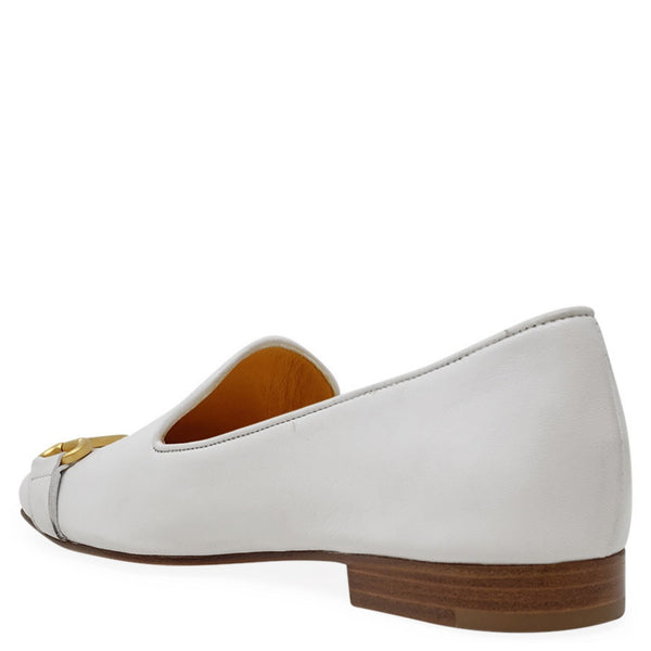 White flat shoe with a gold accent on a white background